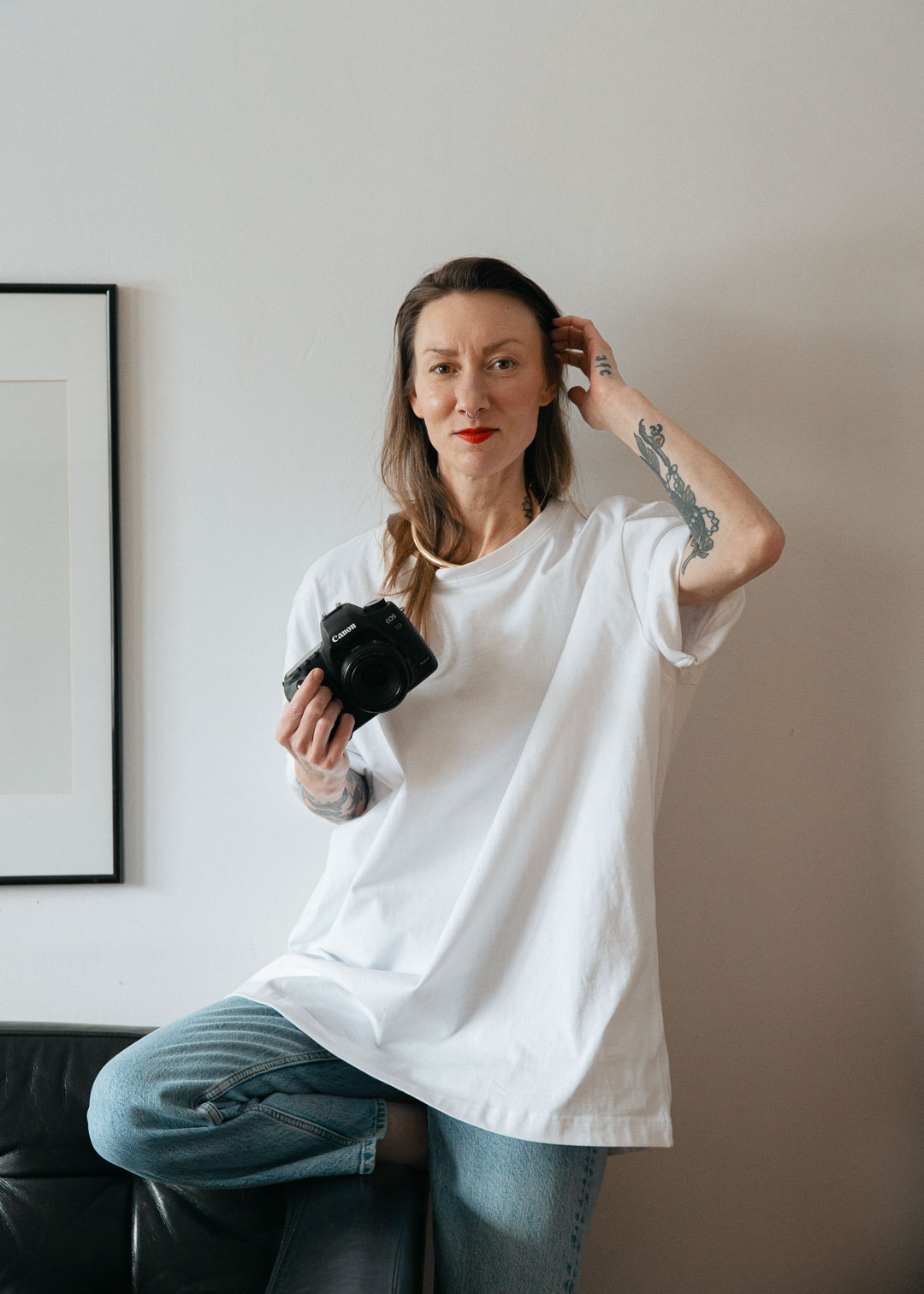 Porträtt av Christine Engström med kamera i vit t-shirt
